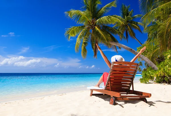 Donna felice seduta sulla sedia a sdraio sulla spiaggia tropicale — Foto Stock