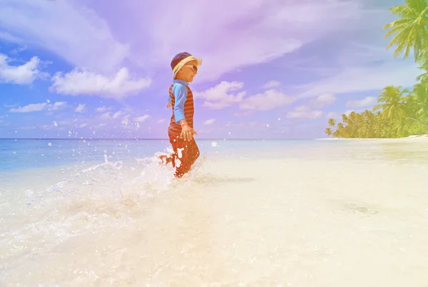 Piccolo ragazzo spruzzi d'acqua sulla spiaggia tropicale — Foto Stock