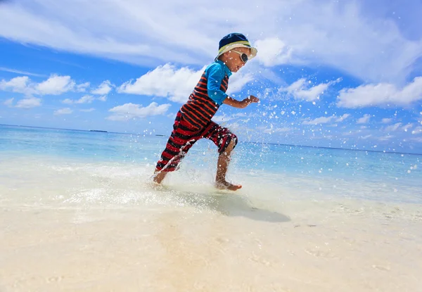 Niño salpicando agua en la playa tropical —  Fotos de Stock