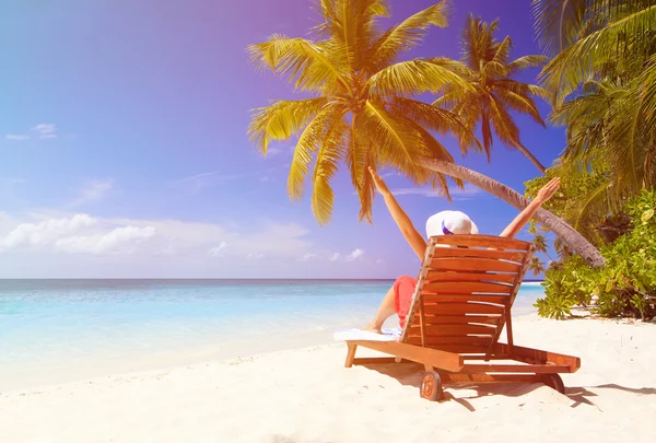 Donna felice seduta sulla sedia a sdraio sulla spiaggia tropicale — Foto Stock