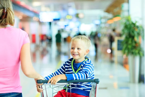 Feliz chico lindo en el aeropuerto montando en el carrito de equipaje — Foto de Stock