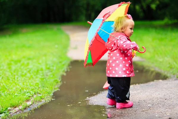 Little girl with umbrella in raincoat and boots outdoor Stock Photo