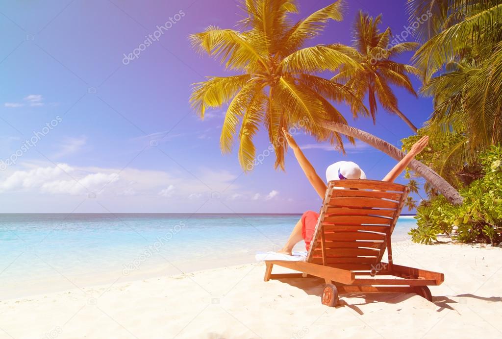 happy woman sitting on beach chair at tropical beach