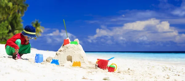 Kleiner Junge baut Sandburg am tropischen Strand — Stockfoto