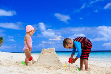 küçük erkek ve kız yaz sahilde sandcastle bina
