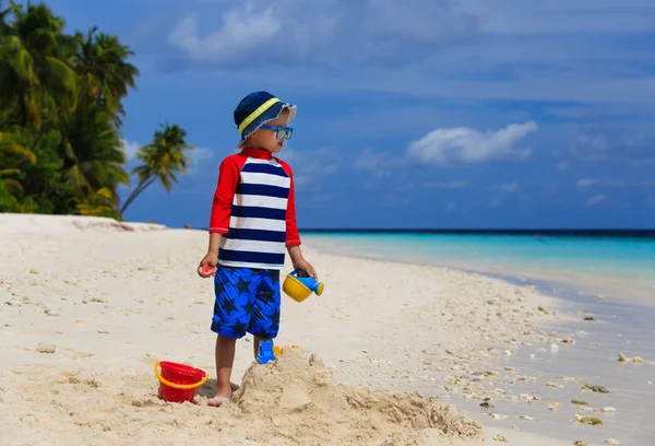 Piccolo ragazzo costruzione castello di sabbia sulla spiaggia tropicale — Foto Stock