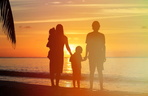 Familia feliz con dos niños en la playa del atardecer — Foto de Stock