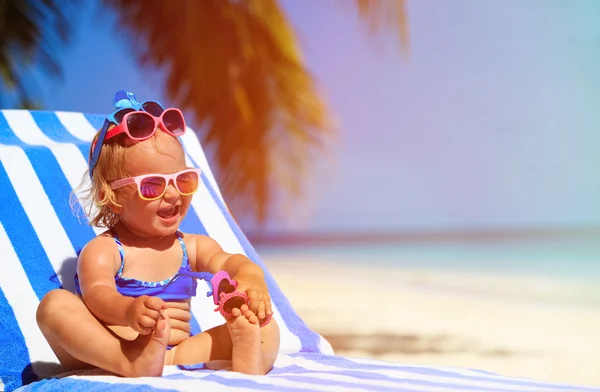 Bonito menina tentando em óculos de sol na praia — Fotografia de Stock