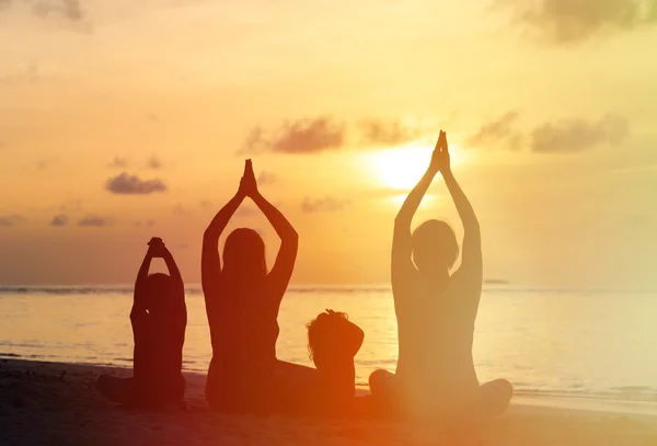 Gün batımında yoga yaparken aile siluetleri — Stok fotoğraf