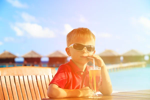 Mały chłopiec, picie soku na tropikalnej plaży — Zdjęcie stockowe