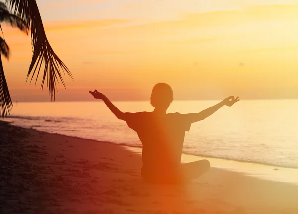 Silhouette of young man meditating at sunset — Stock Photo, Image