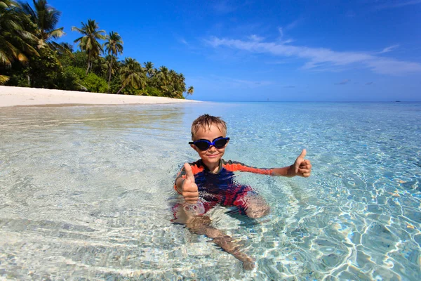 Happy little boy swimming on tropical beach Stock Picture