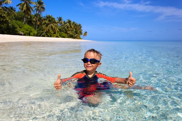 Happy little boy swimming on tropical beach Stock Image