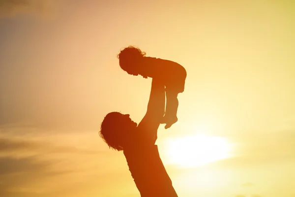 Silhuetas de pai e filha brincando ao pôr do sol — Fotografia de Stock