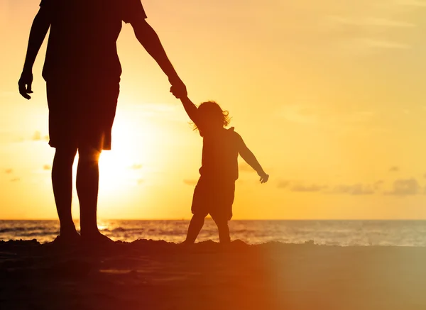 Silhuetas de pai e filha caminhando ao pôr do sol — Fotografia de Stock