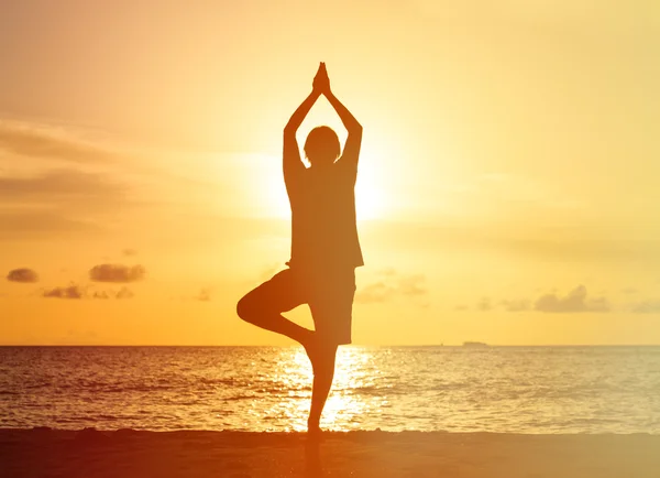 Silhouet van jonge man doen yoga bij zonsondergang — Stockfoto