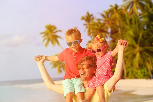 Gelukkig vader met twee kinderen op schouders plezier op strand — Stockfoto