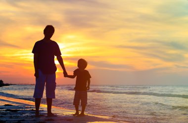 Baba ve oğul günbatımında elele