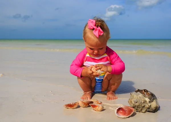 Meisje spelen met schelpen op zomer strand — Stockfoto