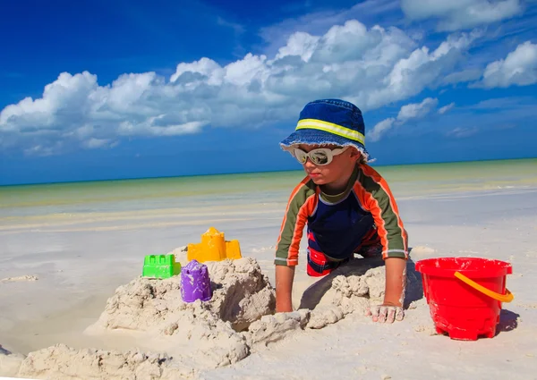 Menino cavando areia na praia tropical — Fotografia de Stock