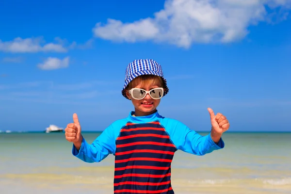 Мальчик поднимает большие пальцы на пляже — стоковое фото