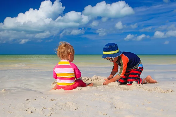 Irmão e irmã brincando com areia na praia — Fotografia de Stock