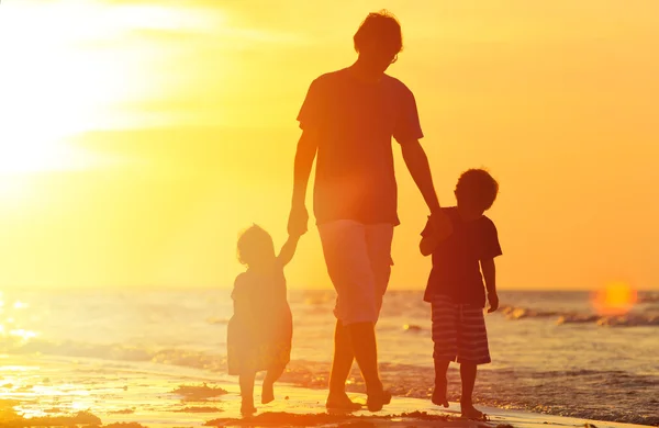 Padre y dos hijos caminando al atardecer — Foto de Stock