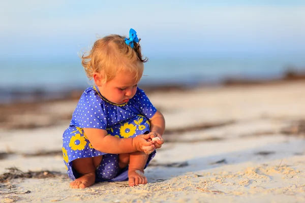 Bambina che gioca con conchiglie sulla spiaggia — Foto Stock