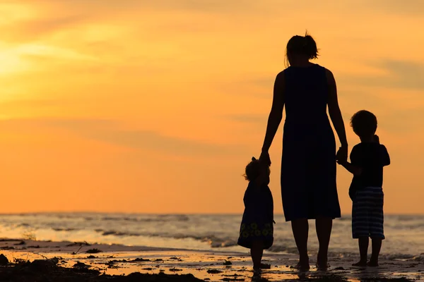 母と夕暮れ時のビーチで歩く二人の子供 — ストック写真