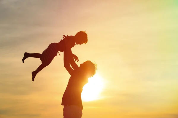 Father and son silhouettes play at sunset — Stock Photo, Image