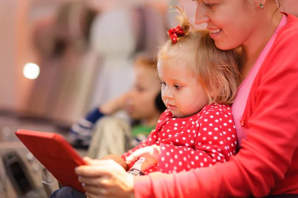 Mutter und kleine Tochter schauen auf Touchpad im Flugzeug — Stockfoto