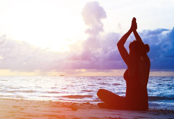 Vrouw meditatie op zonsondergang strand — Stockfoto