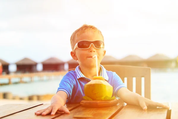 Menino bebendo coquetel de coco na praia tropical — Fotografia de Stock