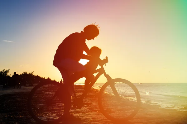 Silhouette de père et bébé faisant du vélo au coucher du soleil — Photo