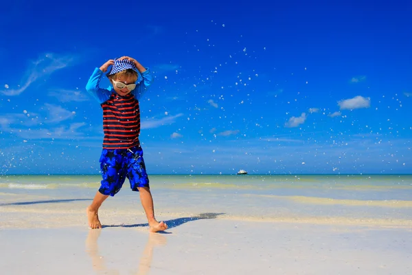 Liten pojke stänk vatten på sommaren beach — Stockfoto