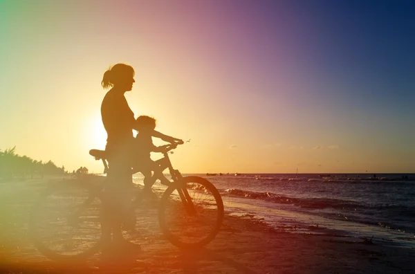 Silhueta de mãe e bebê de bicicleta ao pôr do sol — Fotografia de Stock