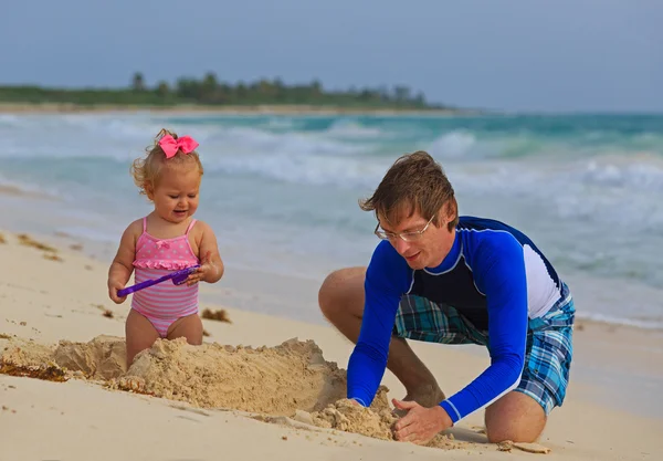 Vader en kleine dochter spelen op tropisch strand — Stockfoto