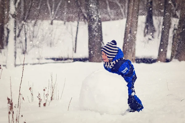 Menino construindo boneco de neve no inverno — Fotografia de Stock