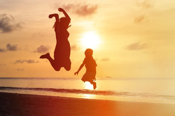 Mãe e filho pulando na praia do pôr do sol — Fotografia de Stock