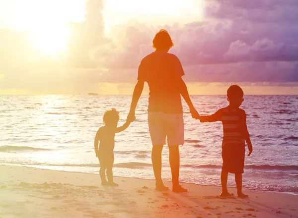 Vader en twee kinderen lopen bij zonsondergang — Stockfoto