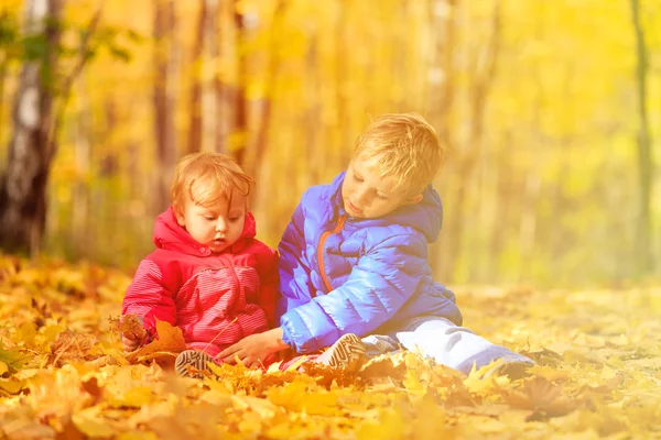 Boy and girl playing in autumn leaves — Stock Photo, Image