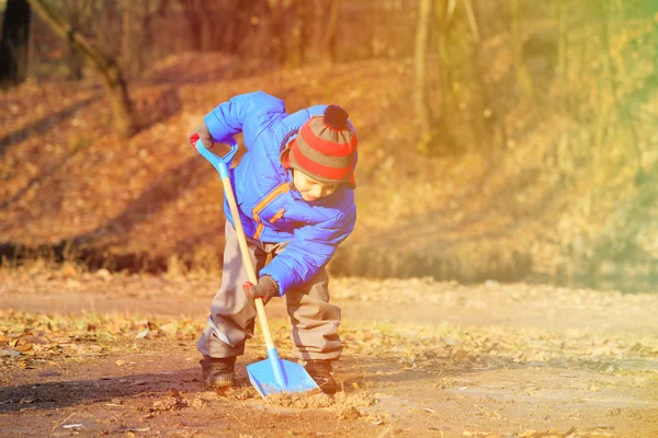 Little boy digging in autumn park — Stock Photo, Image