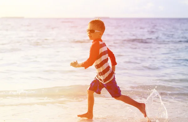Mały chłopiec biegną rozpryskujących na plaży — Zdjęcie stockowe