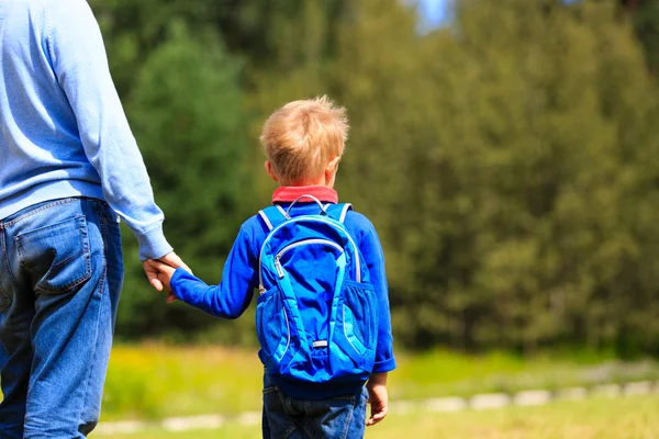 Vater hält Hand seines kleinen Sohnes mit Rucksack im Freien — Stockfoto