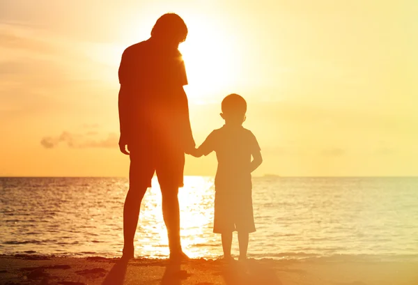Silhouettes de père et fils tenant la main au coucher du soleil — Photo