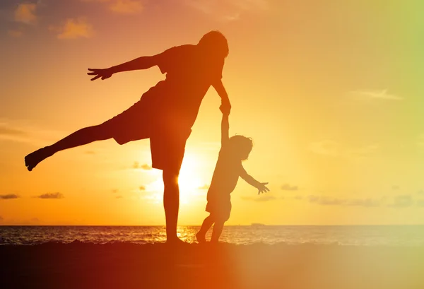 Silhouettes de père et petite fille jouent au coucher du soleil — Photo