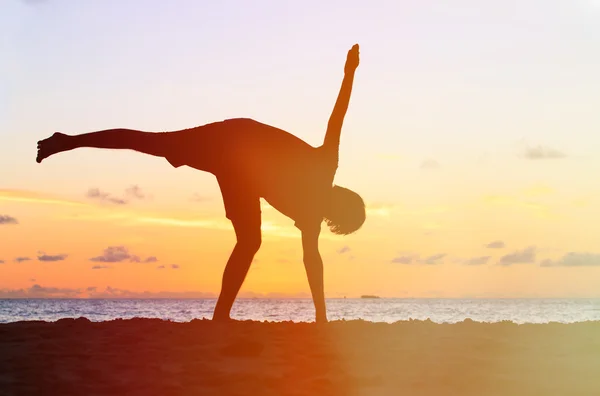 Silhouet van jonge man doen yoga bij zonsondergang — Stockfoto