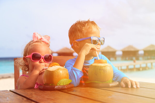 little boy and girl drinking coconut cocktail on tropical resort