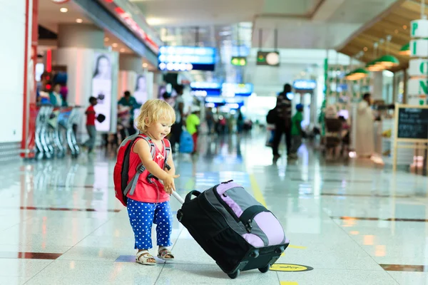 Liten flicka med resväska resor på flygplatsen — Stockfoto