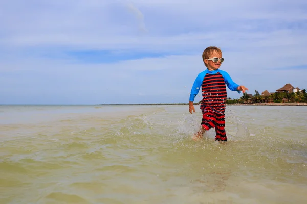 Malý chlapec hraje s vodou na letní beach — Stock fotografie